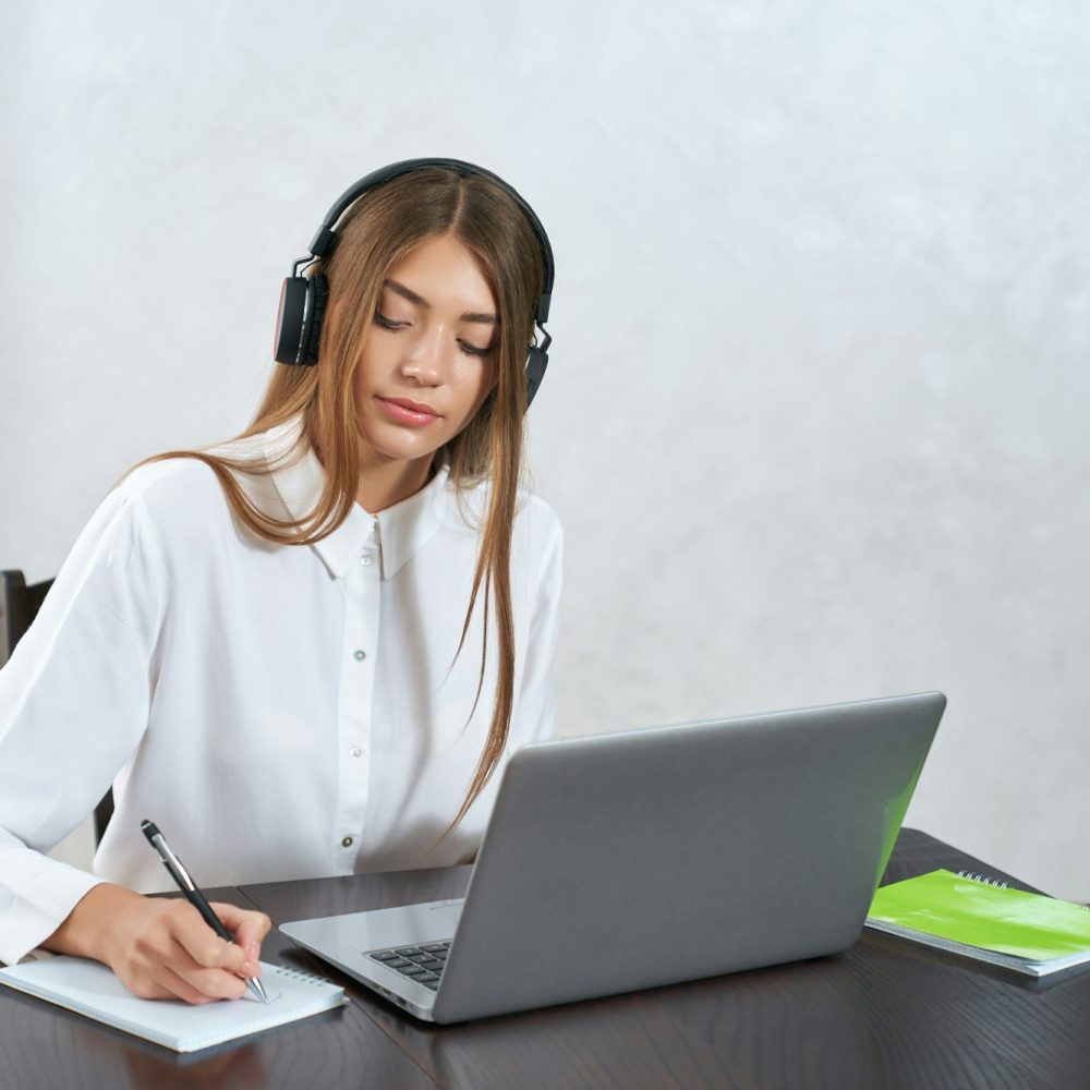 Charming woman listening online courses in headphones